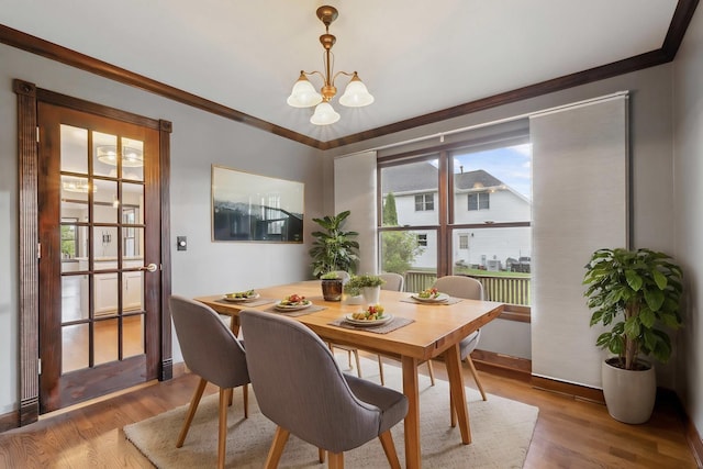 dining space with a chandelier, crown molding, wood finished floors, and baseboards