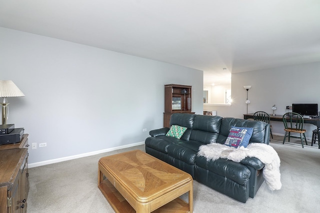 living area featuring baseboards and light carpet
