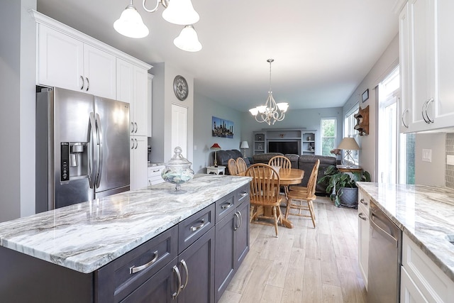 kitchen featuring open floor plan, light wood-type flooring, white cabinets, a chandelier, and stainless steel appliances