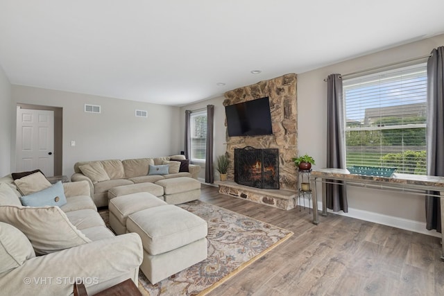 living area featuring visible vents, baseboards, wood finished floors, and a fireplace