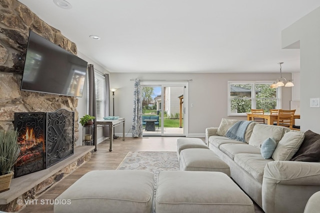 living room featuring baseboards, a chandelier, wood finished floors, and a wealth of natural light