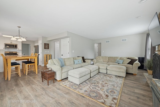 living room with visible vents, baseboards, and wood finished floors