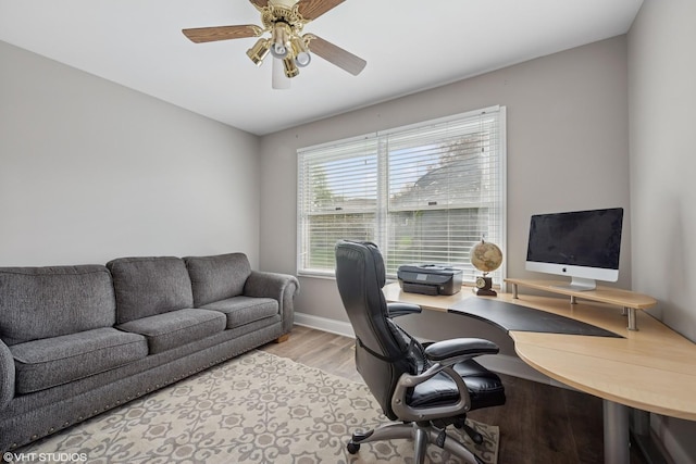 home office with baseboards, a ceiling fan, and light wood-style flooring