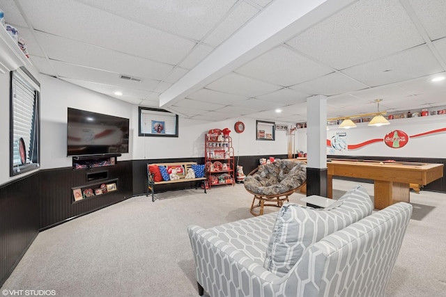 recreation room featuring a drop ceiling, carpet, and a wainscoted wall