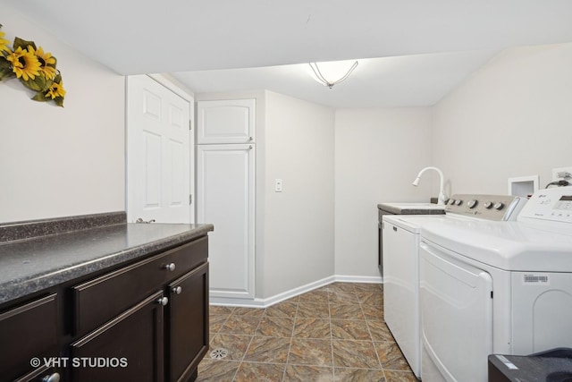 laundry area featuring separate washer and dryer, a sink, cabinet space, and baseboards