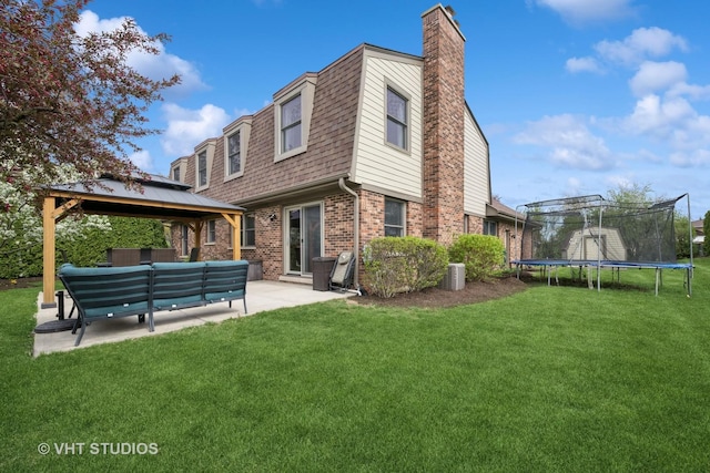 rear view of property featuring a chimney, a trampoline, a patio area, brick siding, and a gazebo