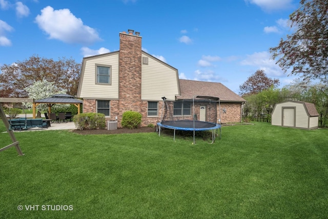 rear view of house featuring a patio, brick siding, a gazebo, a trampoline, and a storage shed
