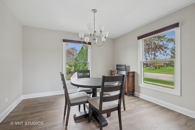 dining space featuring baseboards, a notable chandelier, a wealth of natural light, and light wood-type flooring