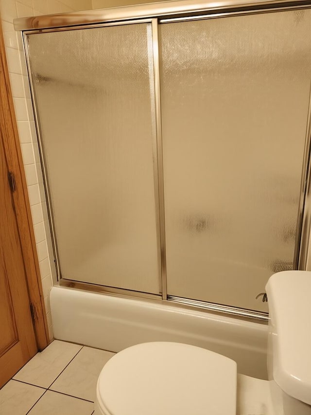 bathroom with toilet, shower / bath combination with glass door, and tile patterned floors