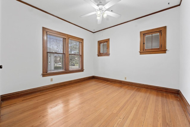 empty room featuring crown molding, baseboards, light wood-type flooring, and a ceiling fan