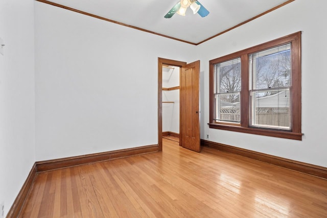 spare room featuring light wood-style flooring, baseboards, ornamental molding, and a ceiling fan