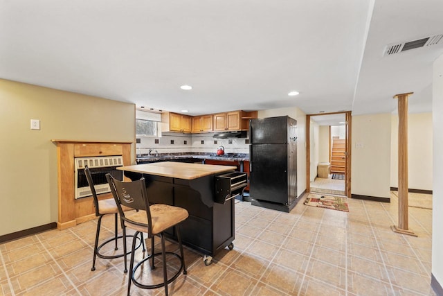 kitchen with recessed lighting, freestanding refrigerator, heating unit, a kitchen island, and visible vents