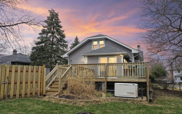 rear view of property featuring a shingled roof, a wooden deck, fence, and stairway