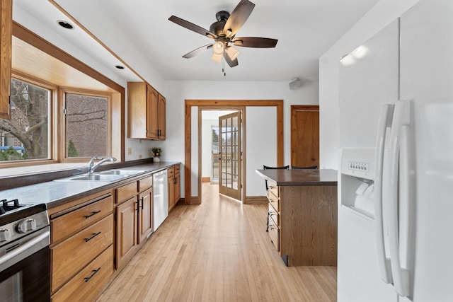 kitchen with a sink, light wood-style floors, appliances with stainless steel finishes, and dark countertops