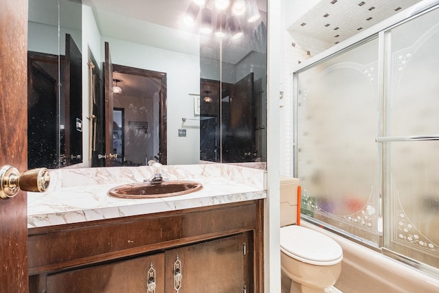 bathroom featuring toilet, vanity, and bath / shower combo with glass door