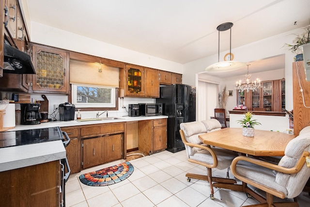 kitchen featuring a sink, black fridge with ice dispenser, an inviting chandelier, light countertops, and stainless steel microwave