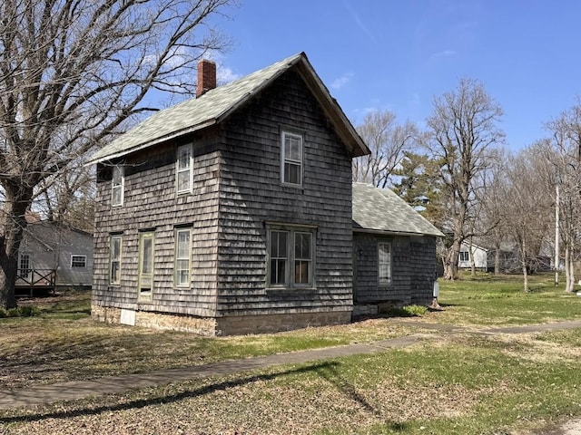 view of property exterior featuring a lawn, a chimney, and roof with shingles