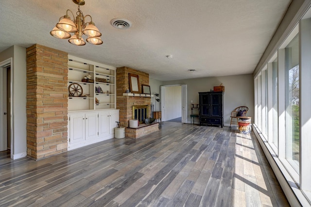 living area with an inviting chandelier, visible vents, a large fireplace, and a healthy amount of sunlight