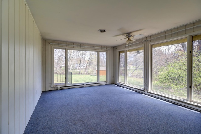 unfurnished sunroom featuring a baseboard heating unit, a wealth of natural light, and visible vents