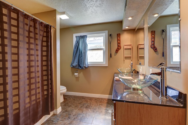 bathroom with recessed lighting, toilet, a sink, baseboards, and a textured ceiling