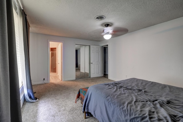 carpeted bedroom featuring baseboards, ensuite bath, visible vents, and a textured ceiling