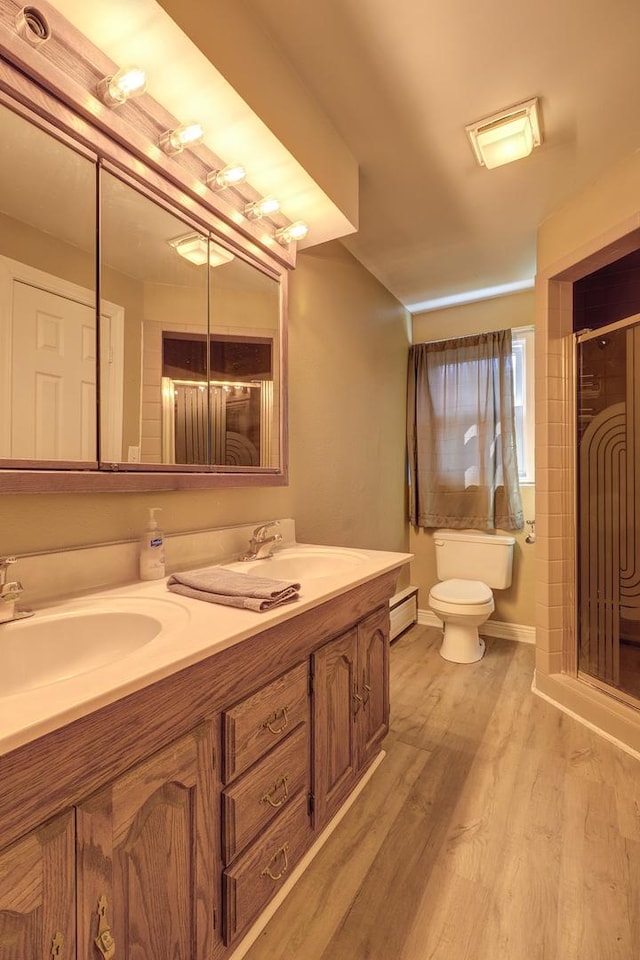 bathroom with double vanity, toilet, wood finished floors, and a sink