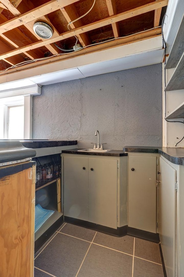 kitchen featuring white cabinets, dark countertops, a sink, and tile patterned floors