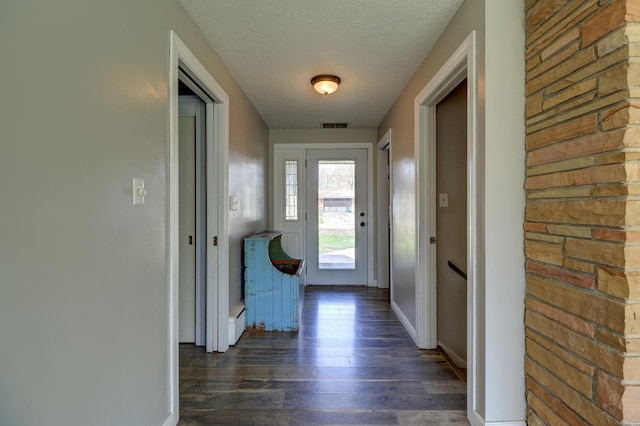 doorway with baseboards, dark wood-style flooring, and visible vents
