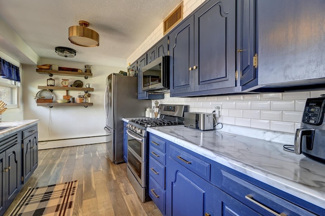 kitchen with a baseboard radiator, tasteful backsplash, dark wood finished floors, appliances with stainless steel finishes, and visible vents