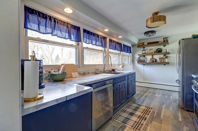 kitchen with dark wood finished floors, blue cabinets, a sink, appliances with stainless steel finishes, and baseboard heating