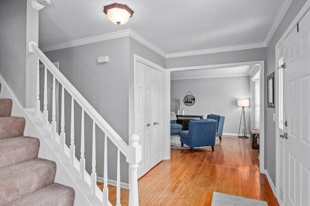 foyer with baseboards, crown molding, hardwood / wood-style floors, and stairway