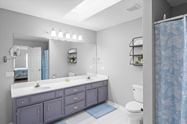 bathroom with toilet, a skylight, visible vents, and a sink