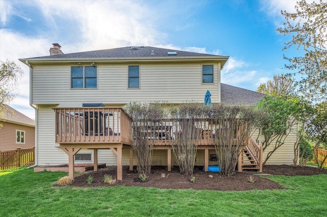 rear view of property featuring a chimney, a yard, and a deck