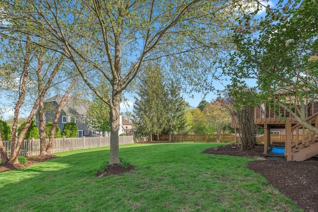 view of yard with a deck, a fenced backyard, and stairs