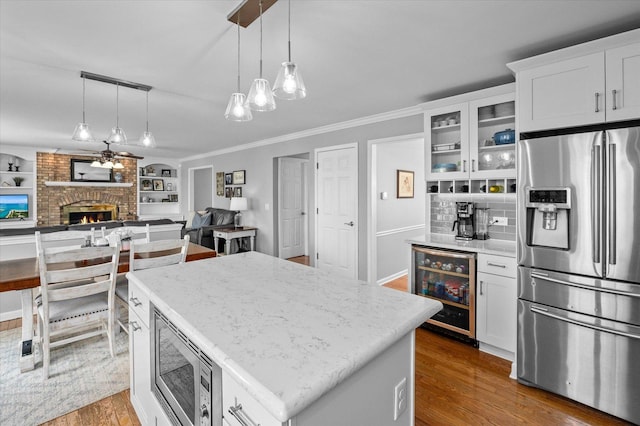 kitchen featuring beverage cooler, appliances with stainless steel finishes, pendant lighting, and wood finished floors