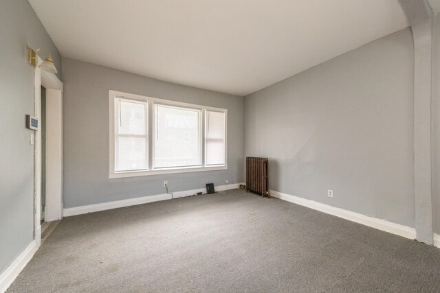 7748 S Saginaw Ave, Chicago, IL 60649 - unfurnished room with radiator heating unit, carpet floors, baseboards, and arched walkways