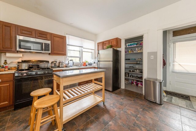 7748 S Saginaw Ave, Chicago, IL 60649 - kitchen featuring stainless steel appliances, dark stone finish floors, light countertops, and brown cabinets