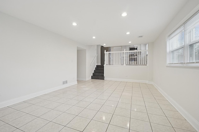 spare room with stairway, light tile patterned floors, visible vents, and recessed lighting