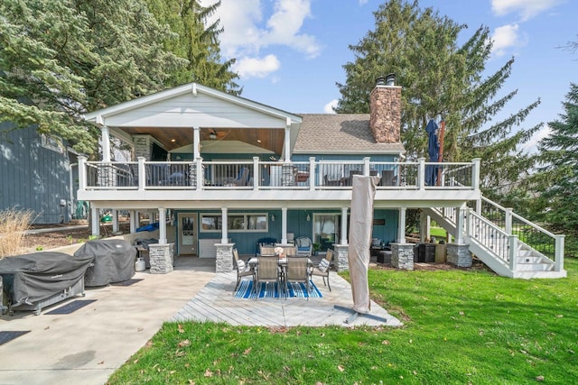 rear view of house featuring a lawn, a chimney, a patio, a wooden deck, and stairs
