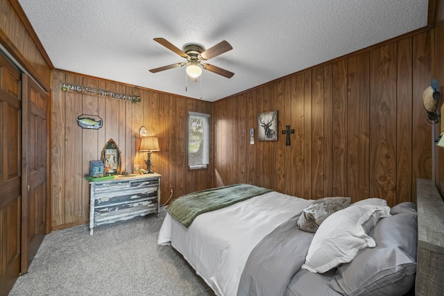 bedroom featuring carpet, a textured ceiling, and wood walls