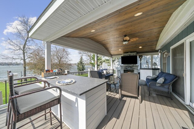 wooden terrace featuring ceiling fan, outdoor lounge area, outdoor dining space, and a water view