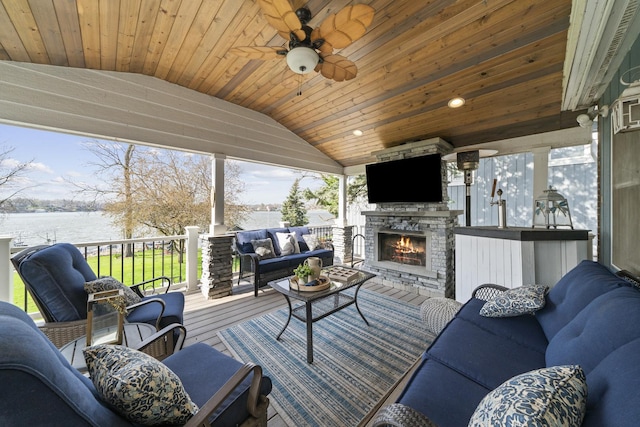 sunroom with a water view, an outdoor living space with a fireplace, and ceiling fan