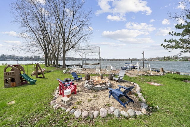 view of yard featuring a fire pit, a water view, and a boat dock