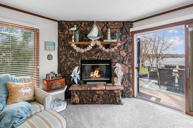 carpeted living area with a stone fireplace, a textured ceiling, and crown molding