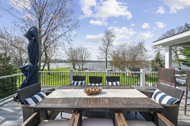 wooden terrace featuring outdoor dining area, a water view, and a yard