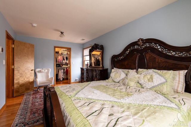 bedroom featuring a closet, baseboards, a walk in closet, and wood finished floors