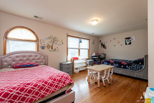 bedroom with visible vents, multiple windows, and light wood-style floors