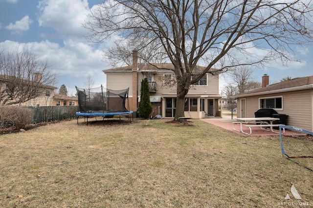rear view of property with a patio area, a yard, a trampoline, a chimney, and fence
