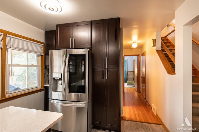 kitchen featuring light wood-style floors, dark brown cabinets, visible vents, stainless steel refrigerator with ice dispenser, and light stone counters
