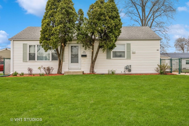 view of front of property featuring roof with shingles, a front lawn, and fence